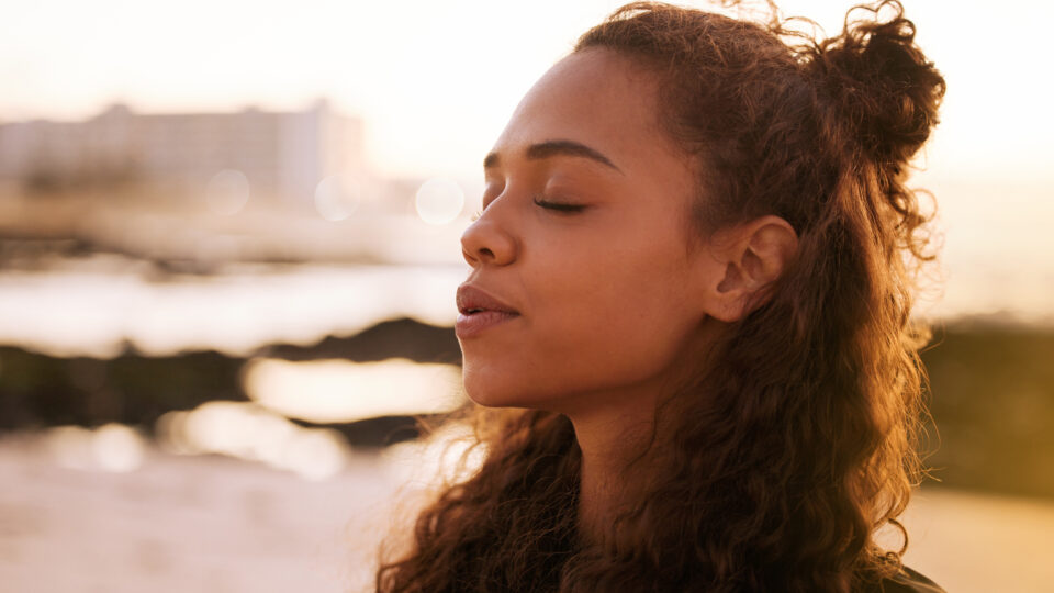 Shot Of An Attractive Young Woman Sitting Alone On A Mat And Meditating On The Beach At Sunset