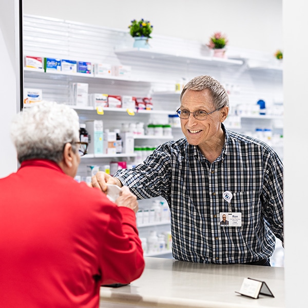 Friendly pharmacist hands medication to a happy woman.