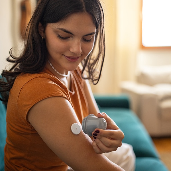 Woman Applying Glucose Sensor On Arm