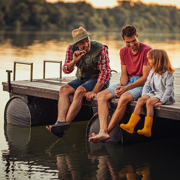 Father and grandfather teach a young girl how to fish.