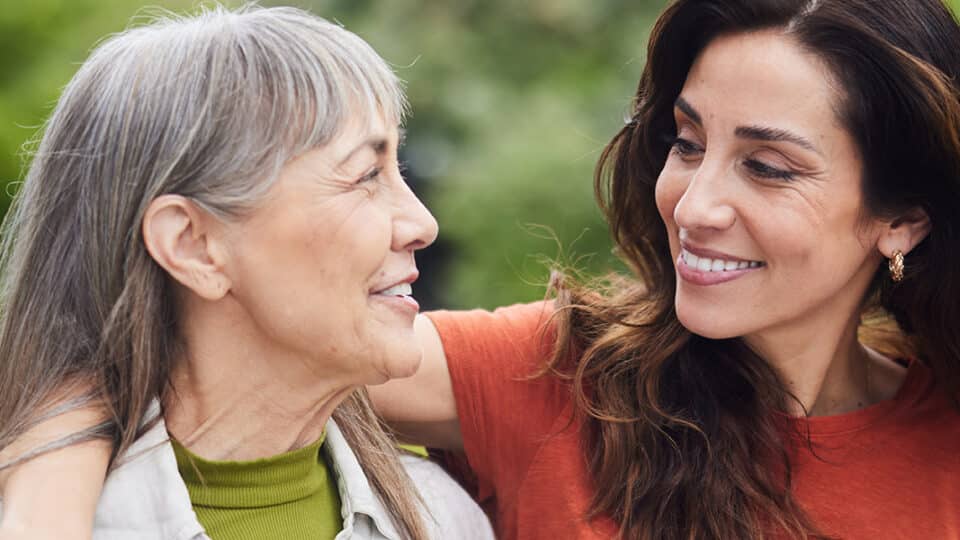 Smiling Woman Talking With Her Senior Mom While Walking Outside