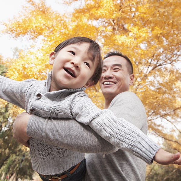 Father And Son Playing Together At The Park In Autumn