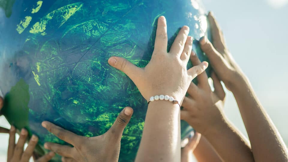 Close Up Of Children Holding A Planet At The Beach